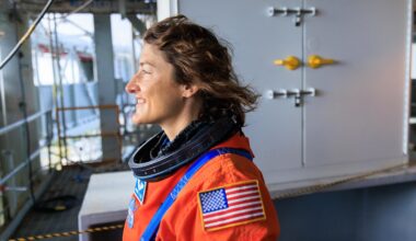 Christina Koch the climber: The astronaut climbs rock and ice on earth. Here she stands and looks out in an orange space suit.