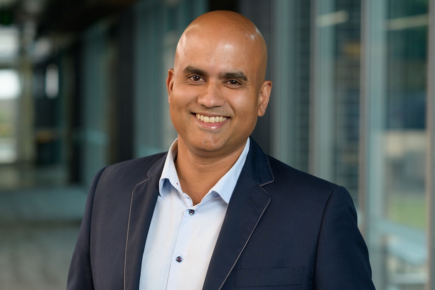 Man in suit smiles at camera.