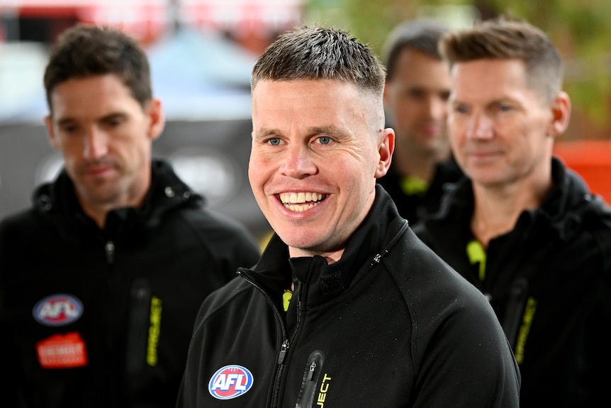 An umpire smiles while being interviewed during a press conference.