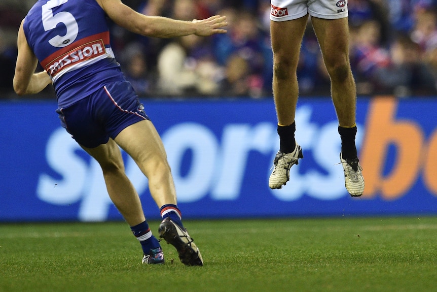 Two AFL players on a field, a sportsbet logo in the background.