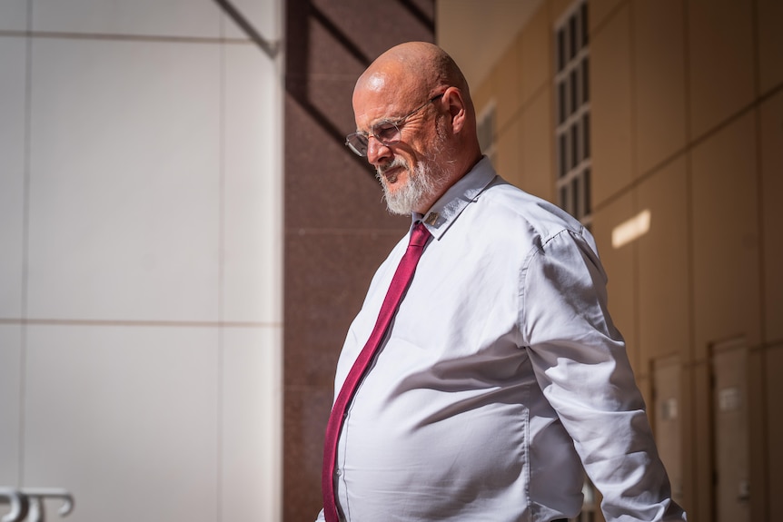 A man in a shirt and tie leaves court