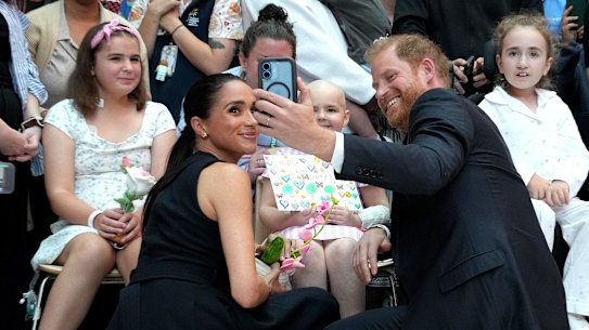 Meghan, Duchess of Sussex and Prince Harry, Duke of Sussex pose for a selfie with children and their families during a visit to the Royal Children’s Hospital.
