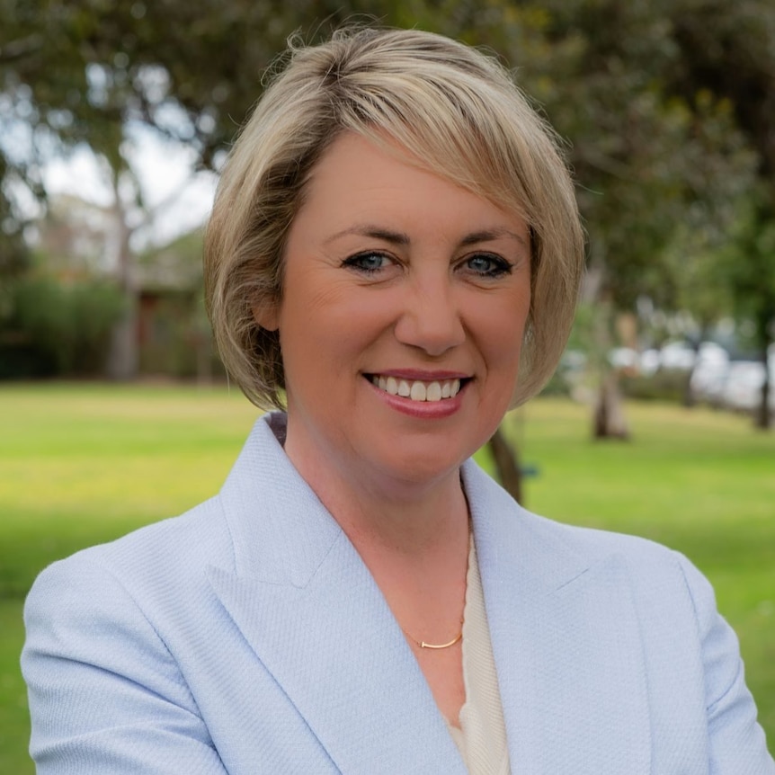 A woman with short blonde hair wearing a white jacket