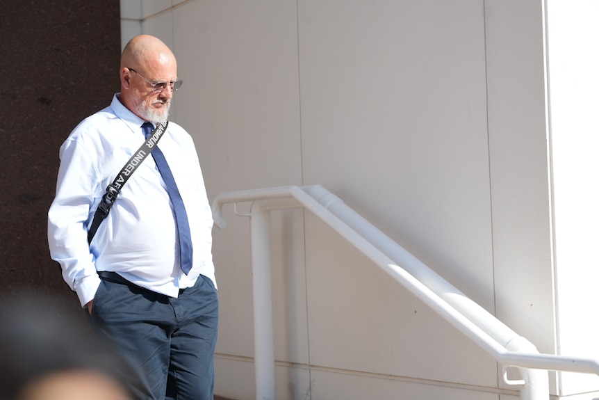 A man in a shirt and tie leaves court.