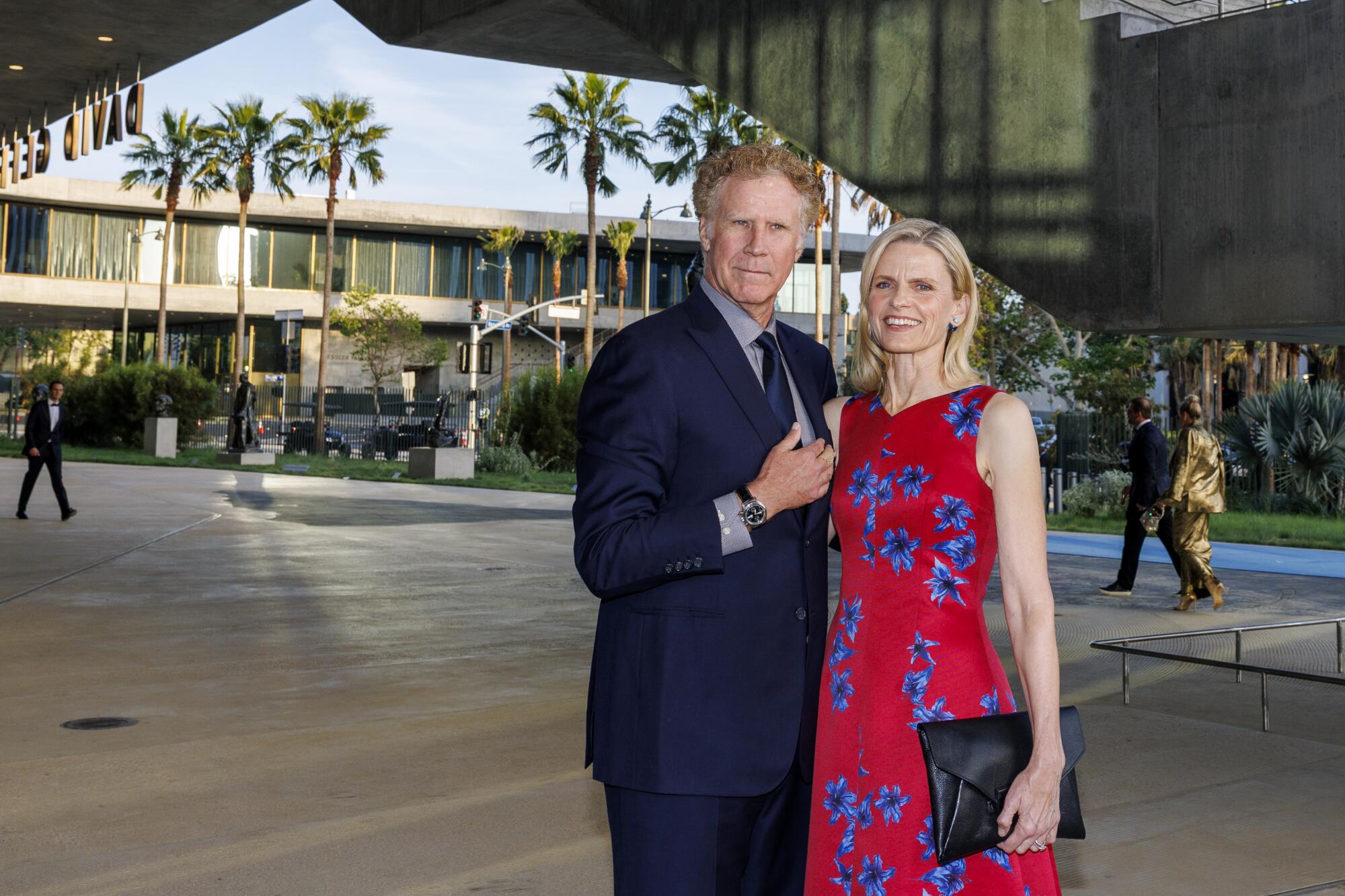 Will Ferrell and Viveca Paulin pose in front of a building.