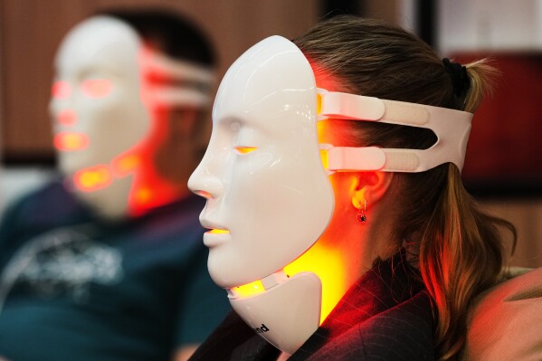 A woman uses a LED face mask for skin regeneration at the health & fitness trade show FIBO in Cologne, Germany, Friday, April 17, 2026. (AP Photo/Martin Meissner)