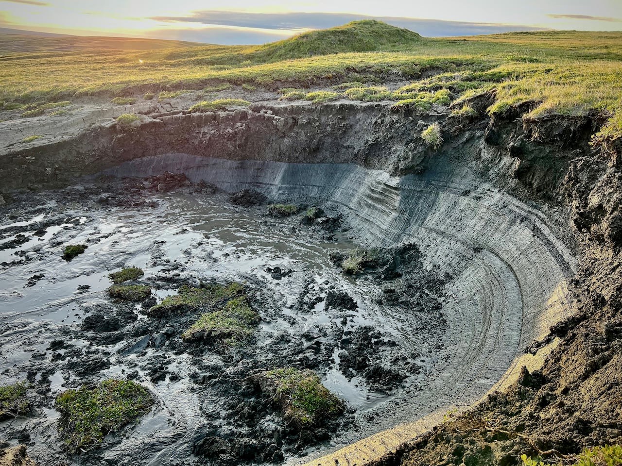 A sunken portion of land with a small cliff within a green landscape.