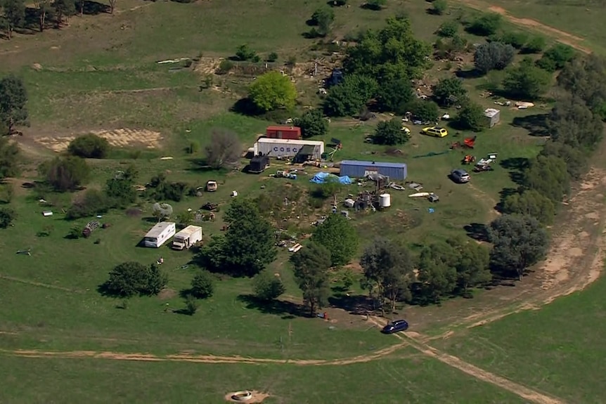 An aerial view of a cluster of buildings and vehicles on a rural property.