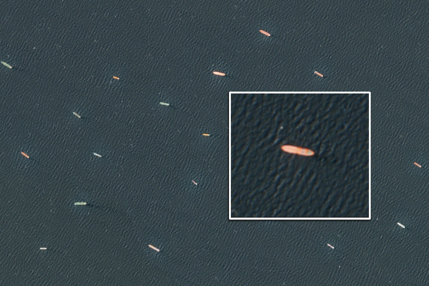 A satellite photo of a lot of large ships floating in the sea.