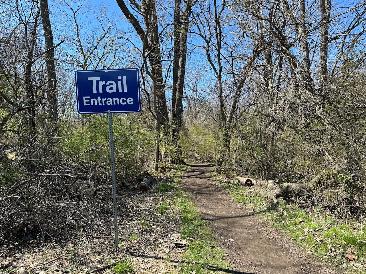 A sign on a trail at a wooded park.