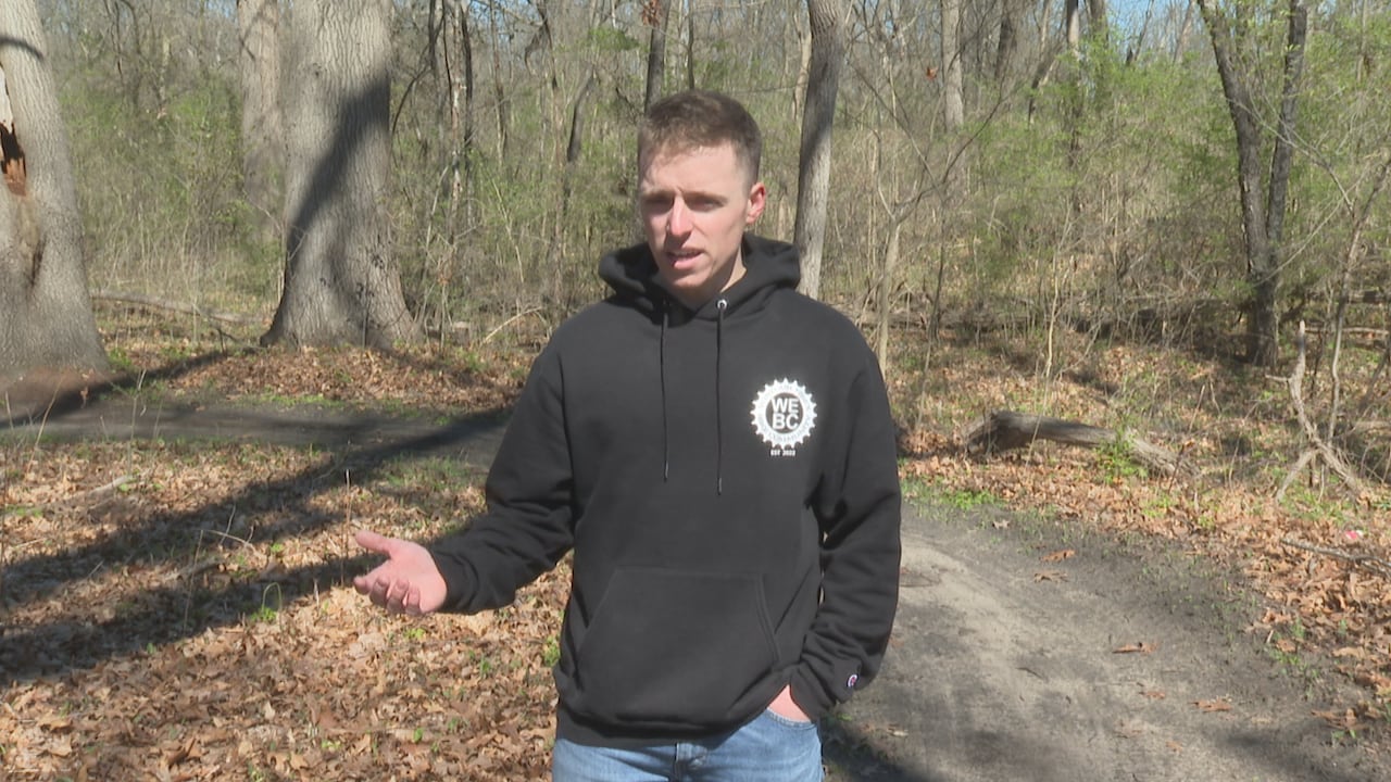 A man on a trail in a wooded area.