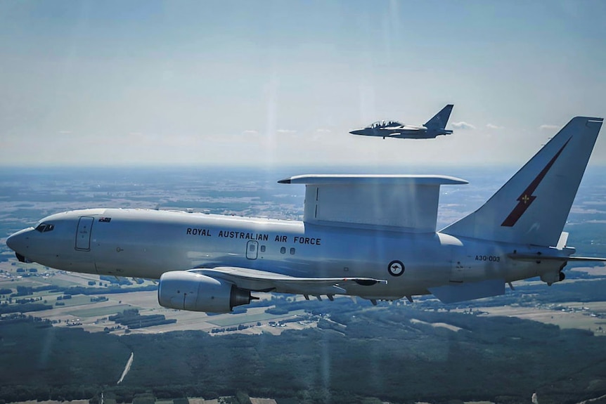 Two planes fly through the sky over farmland