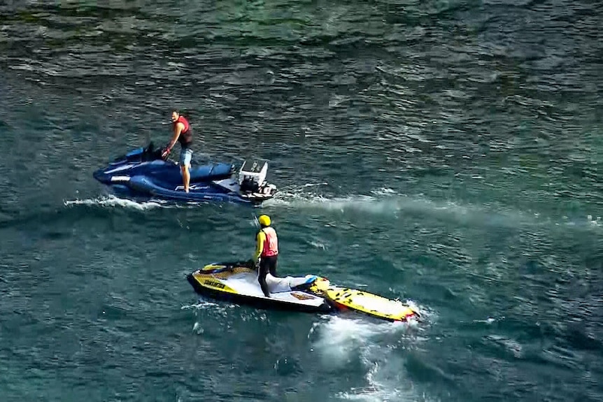Two jet skis on the water conducting shark patrols after increased activity around a whale carcass.
