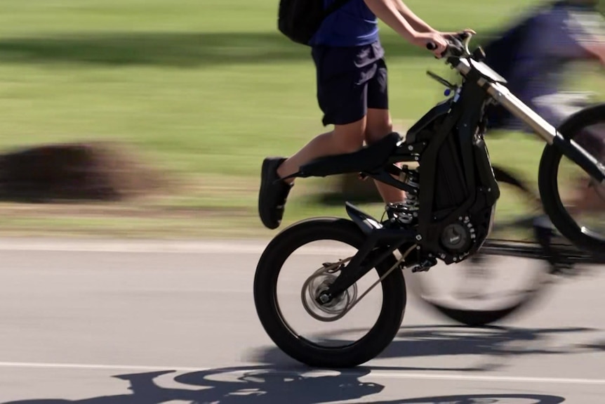 An action shot of an e-bike rider performing a wheelie