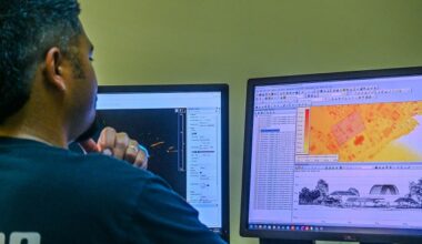 A man sitting at a desk and looking at a computer screen, on which is displayed LiDAR survey mapping data