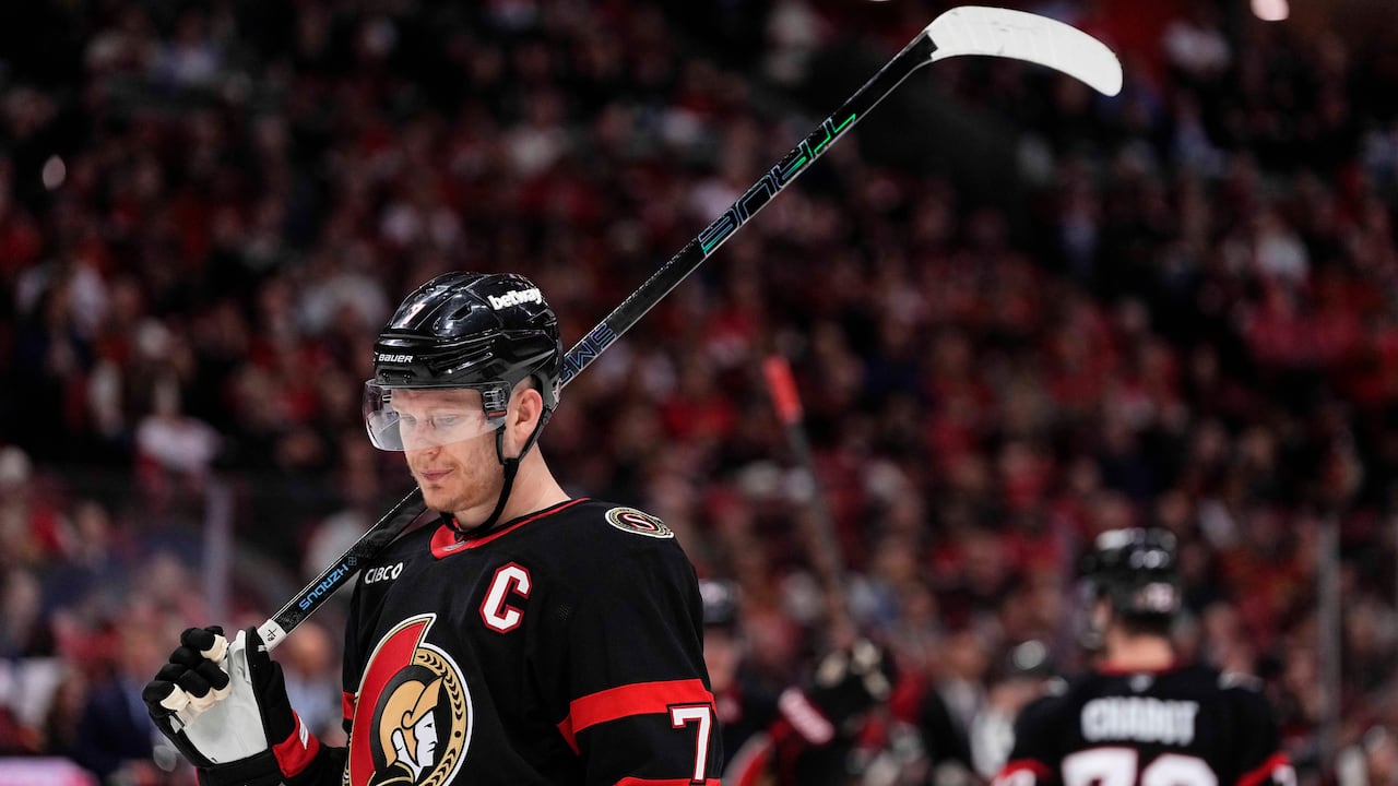 A hockey player rests his stick on his shoulder during a break in play.