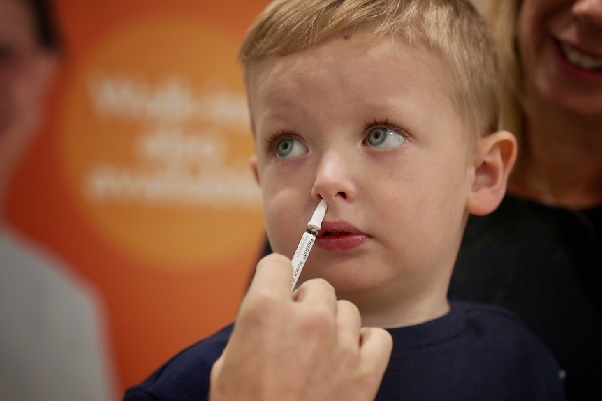 A young child receives a nasal spray