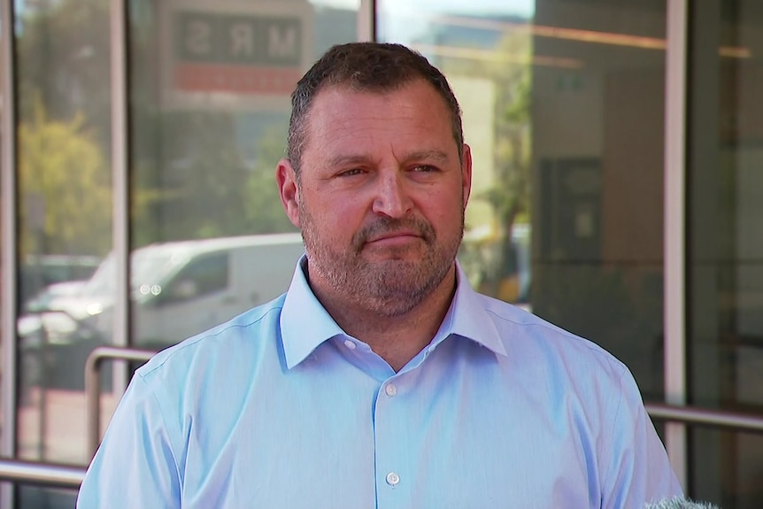 carlos quaremba in a shirt outside a building with glass walls