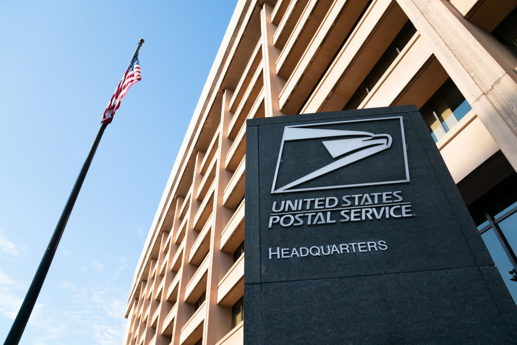An American flag flies above signage outside U.S. Postal Service headquarters in Washington, D.C., on Aug. 17, 2020. —Erin Scott—Bloomberg/Getty Images
