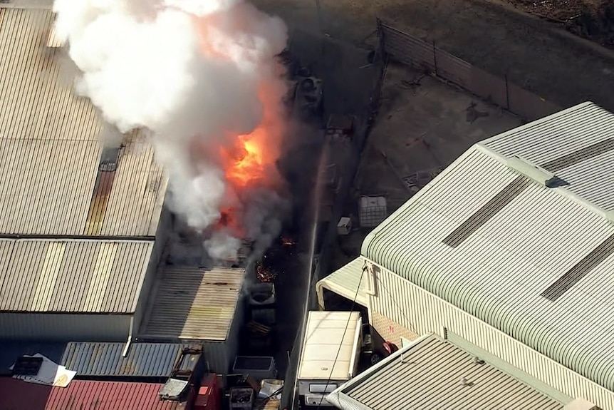 Flames can be seen billowing from a building in an industrial area.
