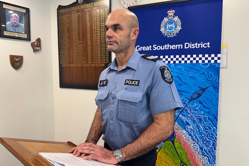 A police officer in blue uniform is speaking to media.