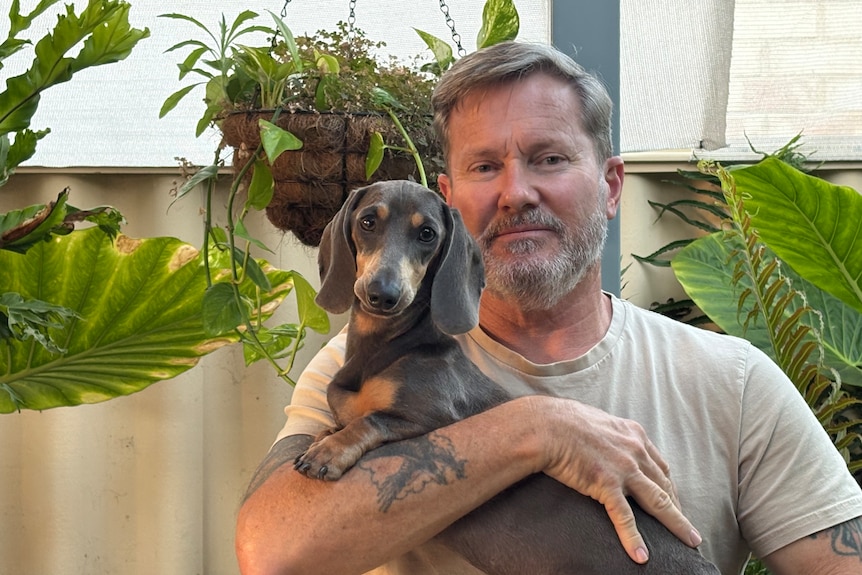 A man holds a small dog. 