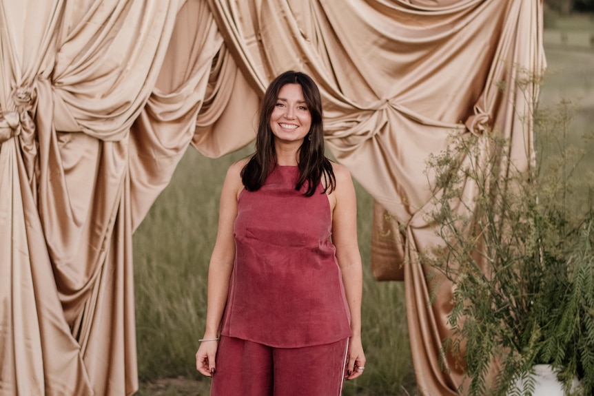 A woman wearing red standing behind a curtain.