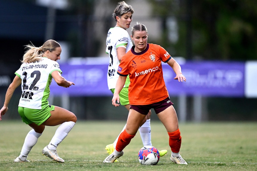 Aimee Medwin kicks the ball around two defenders.