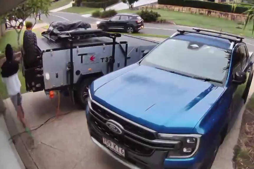 A person in a black and white doodie near a blue Ford Ranger.