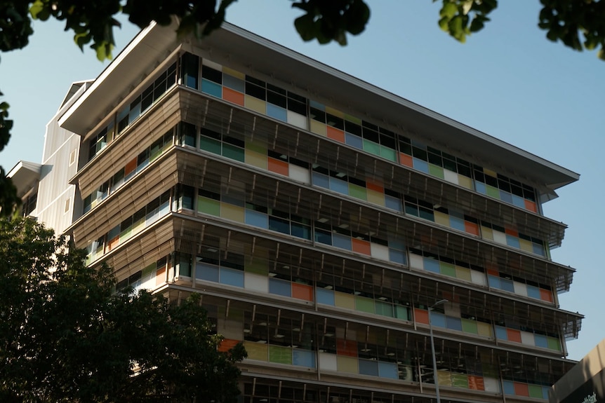 An office building with at least seven floors. The building has multi-coloured cladding.