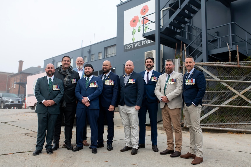 Group of men wearing suits with military medals. 