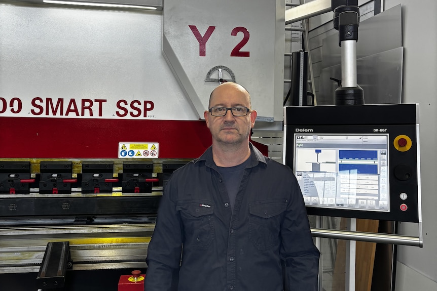 A man standing near heavy manufacturing equipment