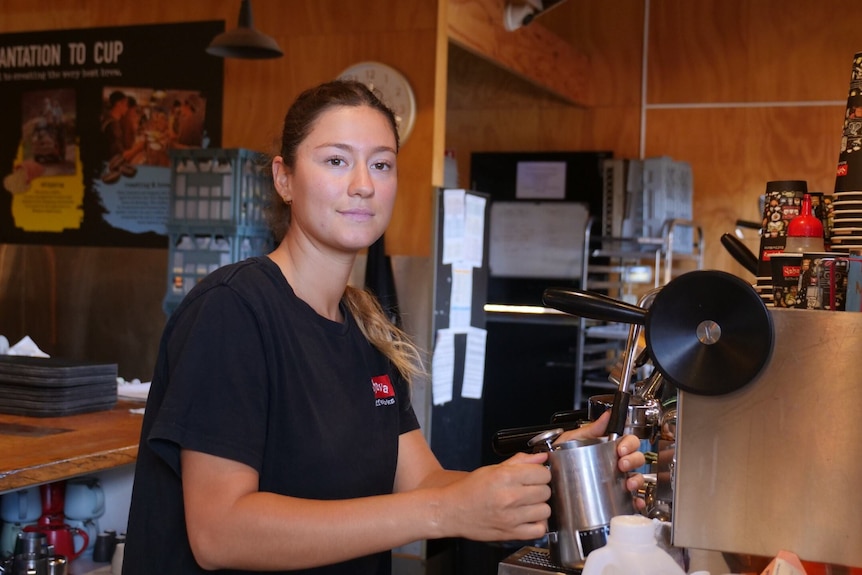 A young woman making coffee in a cafe.