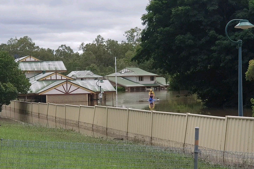 Two people kyak in flood waters in the driveway of the complex. 