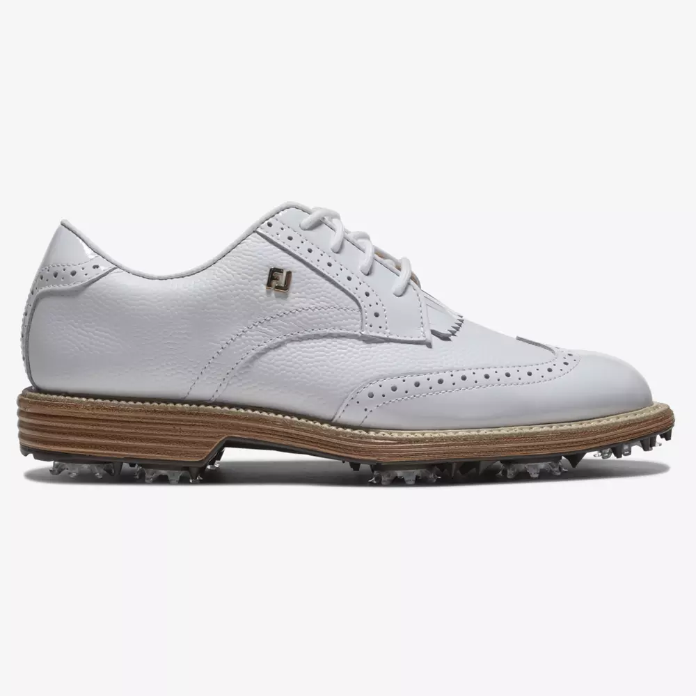 A white leather golf shoe with wingtip design, perforated detailing, white laces, tan midsole, and spiked sole. An FJ logo is visible near the ankle—crafted for performance among the best golf shoes 2026. The background is plain white.