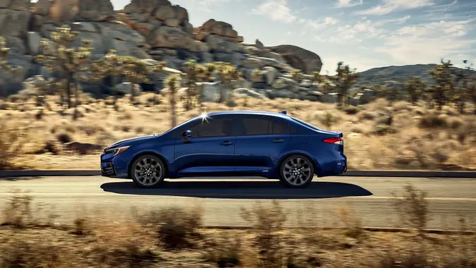 2025 Toyota Corolla Hybrid driving on a desert road for promotional photo.