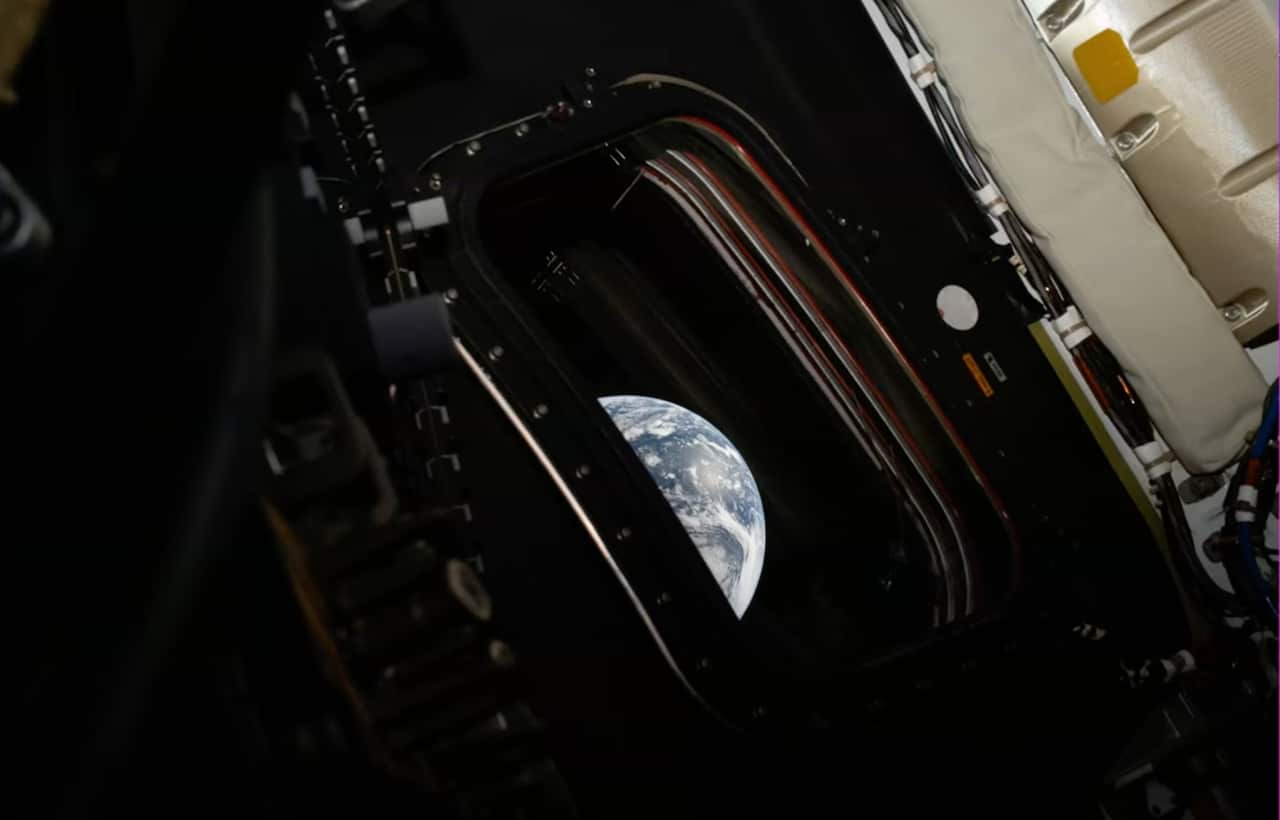 An image of Earth taken through the window of a space craft. The Earth is partially obscured by the window. 