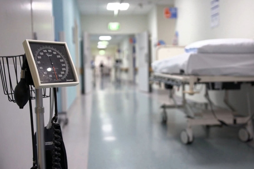 an empty bed and a blood pressure monitor in a hospital corridor 