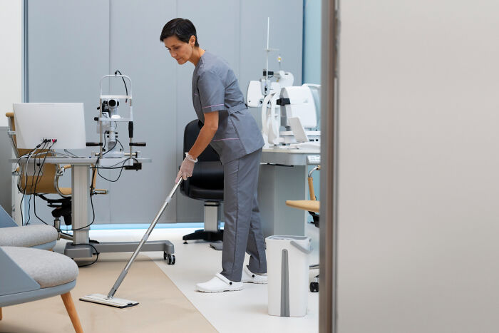 Hospital cleaning staff in uniform sanitizing a medical examination room, highlighting hidden hospital truths and care standards.