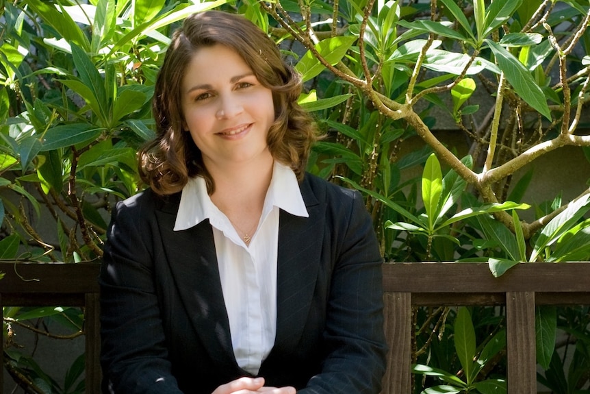 Woman seated in front of garden.