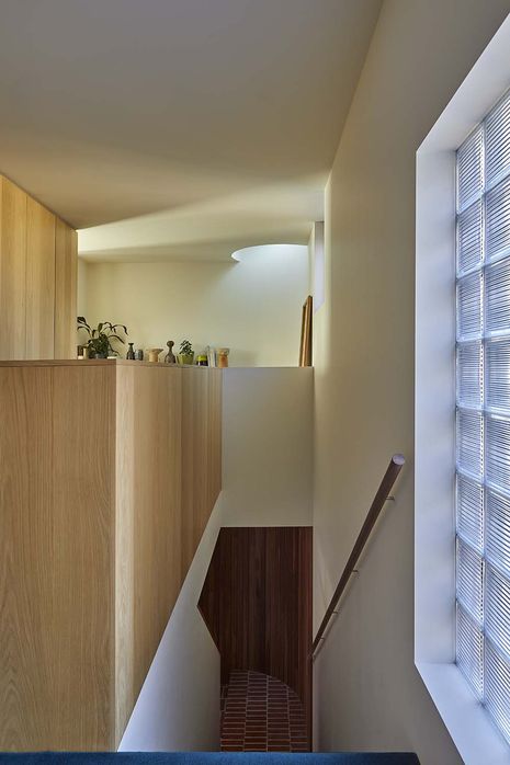 A glass-brick window and skylight manage privacy and access to light in first-floor rooms.