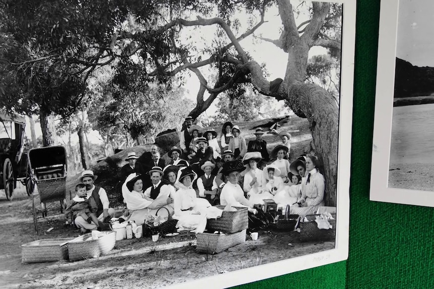 A black-and-white photograph of people having a picnic in early 1900s dress