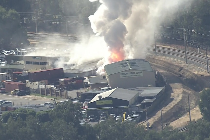 Flames can be seen billowing from a building in an industrial area.