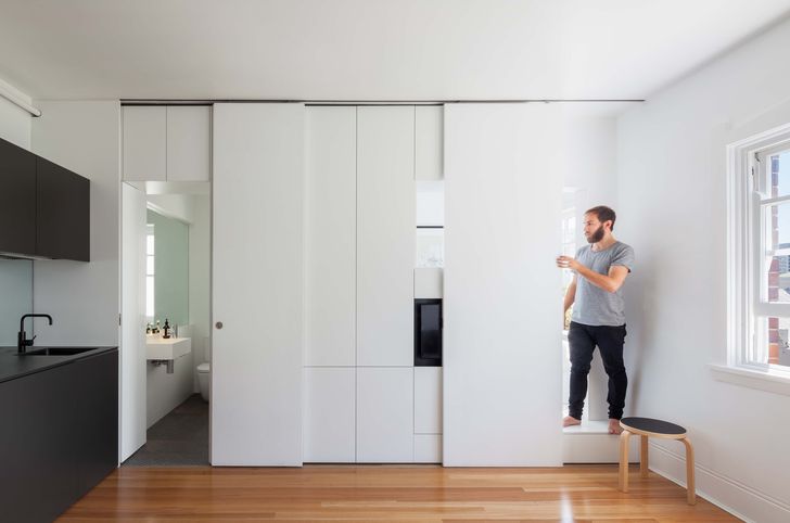 Sliding panels conceal storage and reveal access to the bathroom and bedroom.