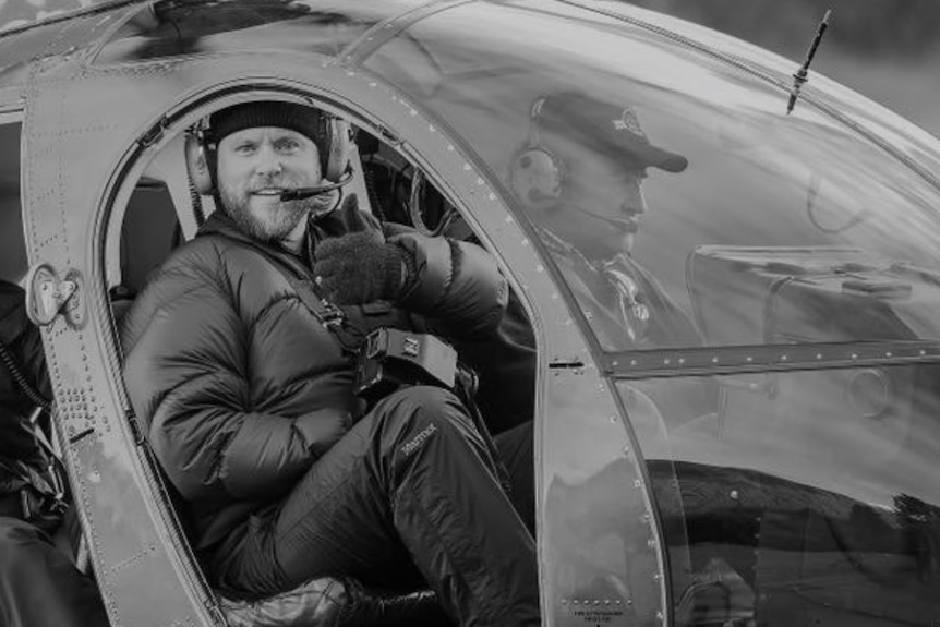 A black and white image of Scott McCook sitting in a helicopter
