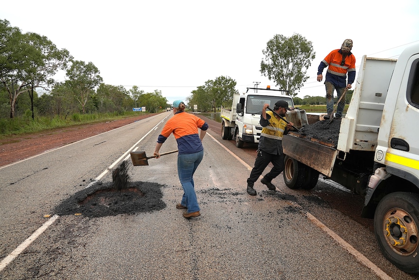 Workers fix a hole in a bitumen road