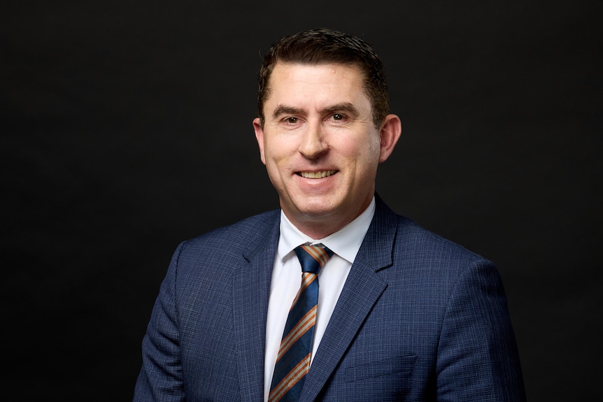 A man wearing a suite smiles.
