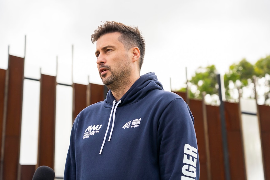 A man standing outside wearing a dark blue hoodie