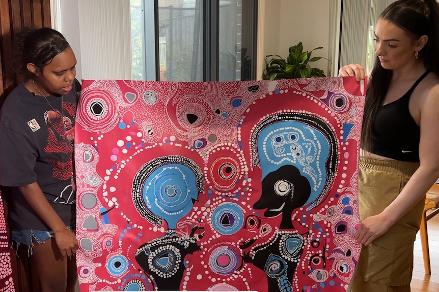 Keira holds one of her paintings with her mum.