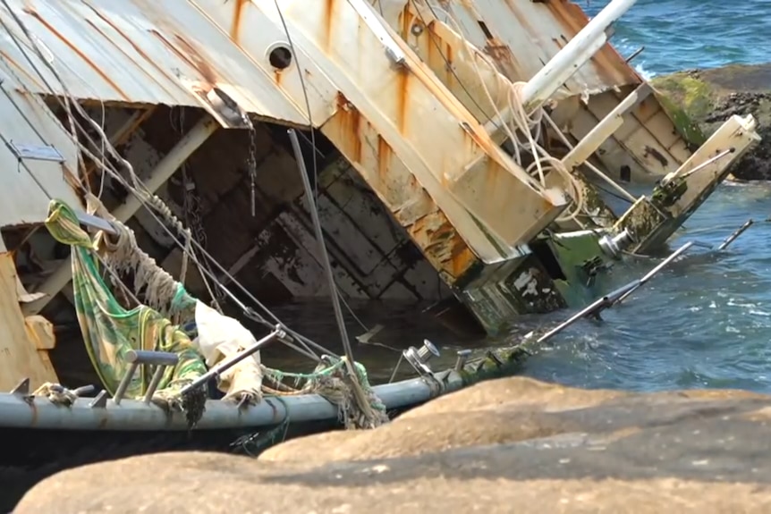 a broken boat stuck on rocks